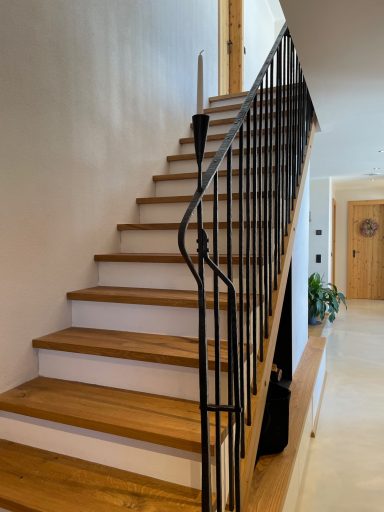Holztreppe mit geschmiedetem Geländer, führend ins erste Stockwerk