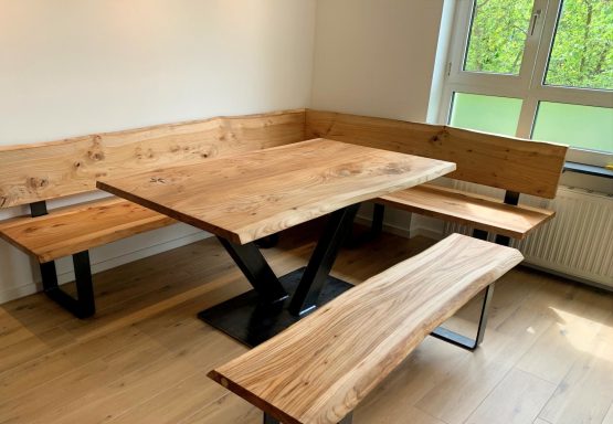 Holztisch mit Sitzbank und Bänken, modern eingerichtet in einem hellen Raum.
