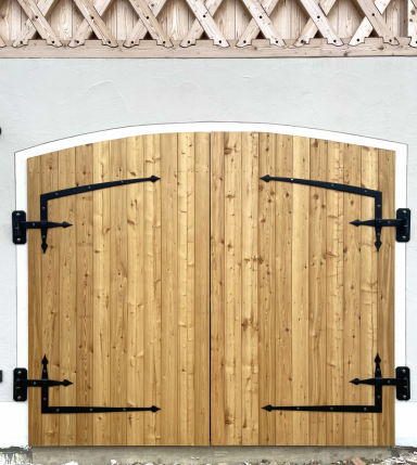 Holztor mit Rundbogen und schwarzen geschmiedeten Torbändern