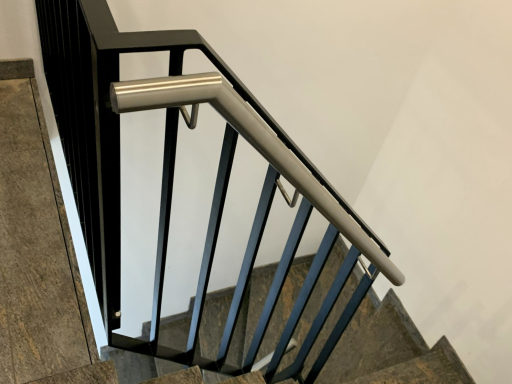 Schwarze Metallgeländer an einer Treppe mit einem Edelstahl Handlauf.