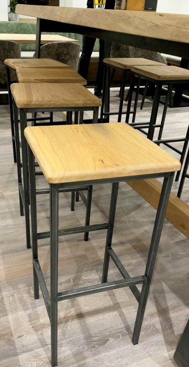 Barhocker mit Holzsitzfläche und metallischem Gestell in einer modernen Einrichtung.